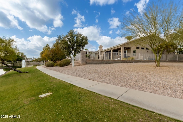 view of property's community with a water view and a lawn