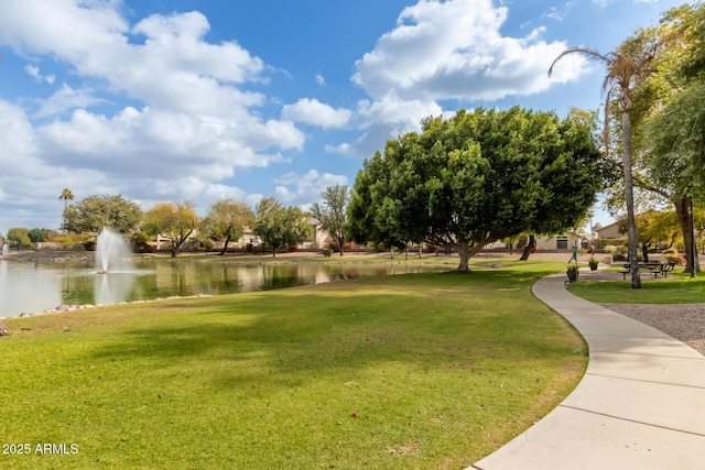 surrounding community with a water view and a lawn