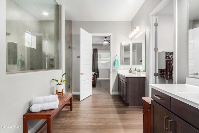 bathroom featuring hardwood / wood-style floors, vanity, a tile shower, and ceiling fan