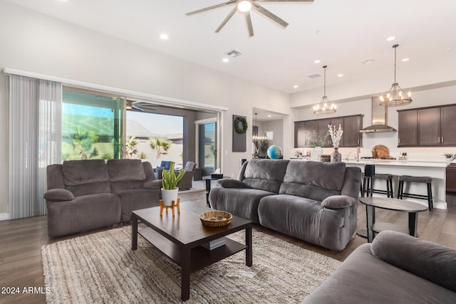 living room with ceiling fan with notable chandelier, light wood-type flooring, and sink