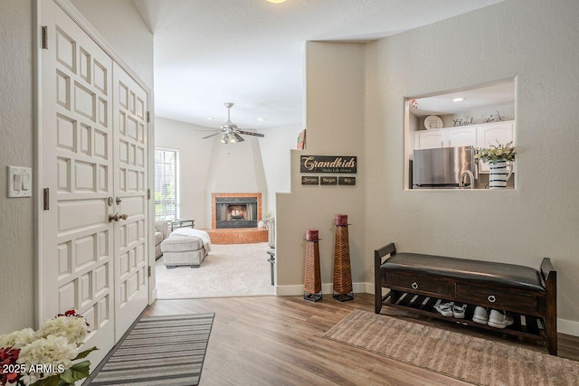 foyer with baseboards, light wood-style flooring, recessed lighting, a fireplace, and ceiling fan