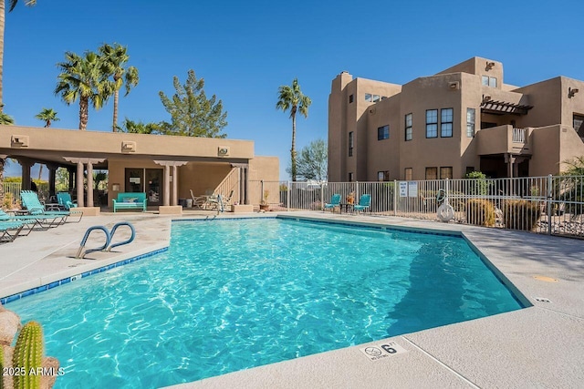 community pool with a patio area and fence