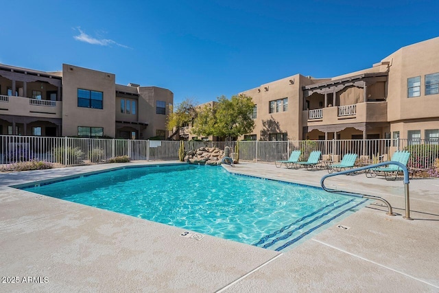 pool with a patio area and fence