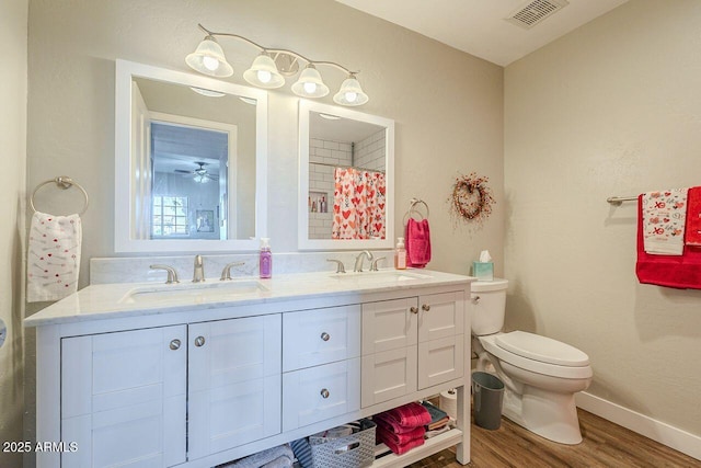 bathroom with visible vents, toilet, wood finished floors, and a sink