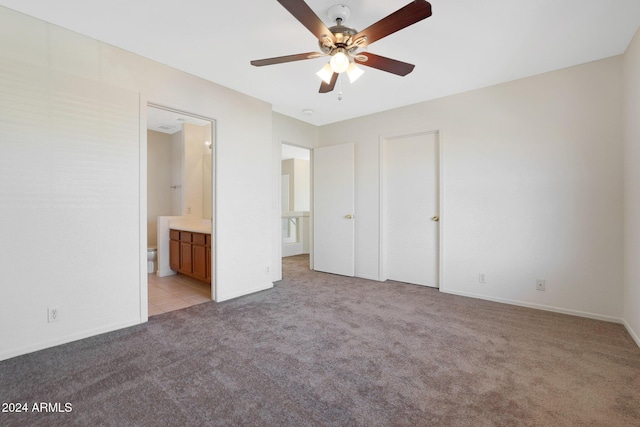 unfurnished bedroom featuring ceiling fan, light colored carpet, and connected bathroom