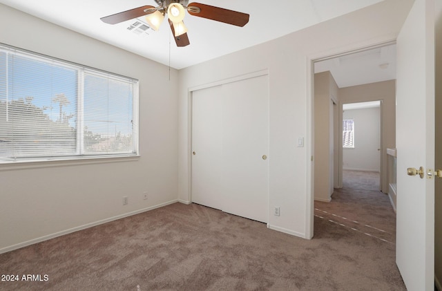 unfurnished bedroom featuring carpet flooring, multiple windows, and ceiling fan