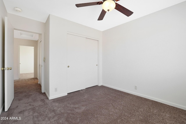 unfurnished bedroom with dark colored carpet, a closet, and ceiling fan