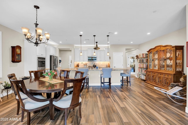 dining area with wood-type flooring and a chandelier