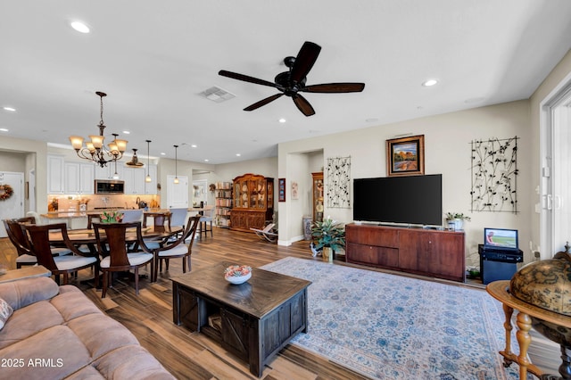 living room with hardwood / wood-style flooring and ceiling fan with notable chandelier