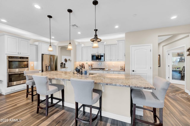 kitchen featuring pendant lighting, white cabinetry, stainless steel appliances, and a large island with sink