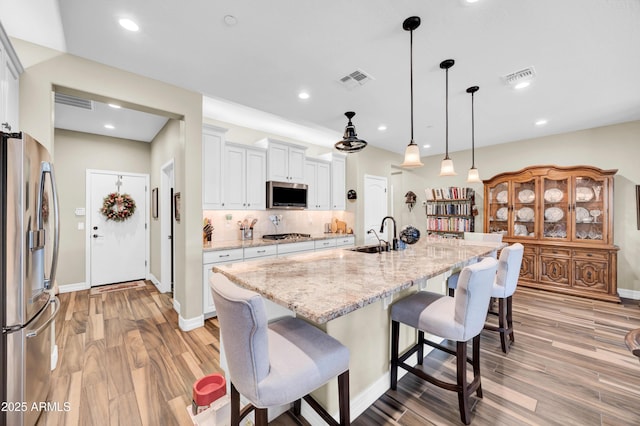 kitchen featuring sink, white cabinetry, an island with sink, pendant lighting, and stainless steel appliances