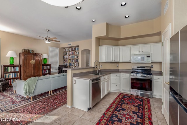 kitchen featuring sink, light tile patterned floors, appliances with stainless steel finishes, white cabinetry, and kitchen peninsula