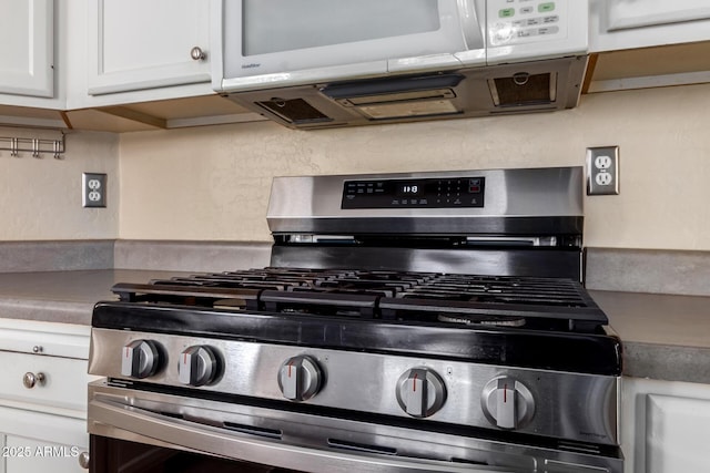 kitchen with stainless steel gas range and white cabinets