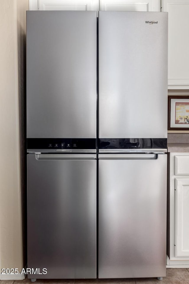 interior details with white cabinetry and stainless steel refrigerator