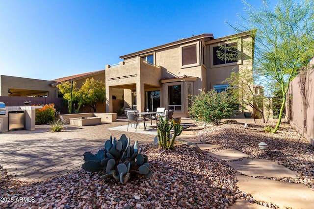 rear view of property with a balcony, exterior kitchen, and a patio area