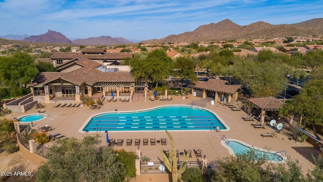 view of swimming pool with a hot tub, a mountain view, and a patio