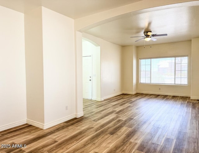 10722 W Quartz Dr, Casa Grande, AZ 85193 - empty room featuring arched walkways, ceiling fan, and wood finished floors