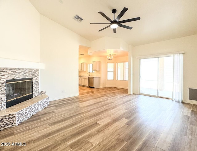 10722 W Quartz Dr, Casa Grande, AZ 85193 - unfurnished living room with a ceiling fan, a tiled fireplace, light wood-style flooring, and a chandelier