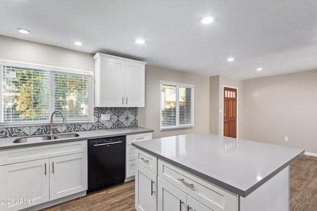 kitchen with backsplash, sink, dishwasher, white cabinets, and a center island