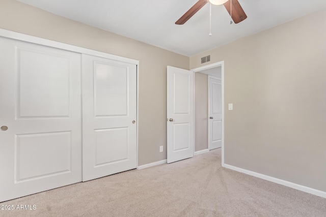 unfurnished bedroom with ceiling fan, a closet, and light carpet