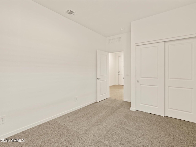 unfurnished bedroom with light carpet and a closet