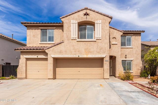 mediterranean / spanish house with fence, driveway, stucco siding, a garage, and a tiled roof