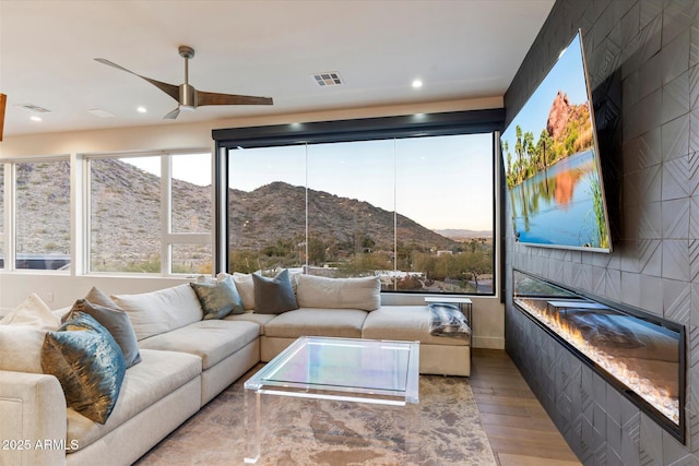 sunroom / solarium with ceiling fan, a healthy amount of sunlight, and a fireplace