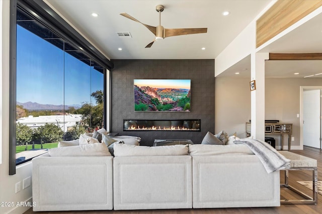 living room with hardwood / wood-style flooring, ceiling fan, and a tile fireplace