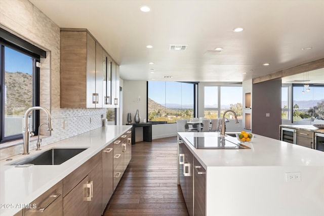 kitchen featuring an island with sink, a mountain view, sink, and black electric stovetop