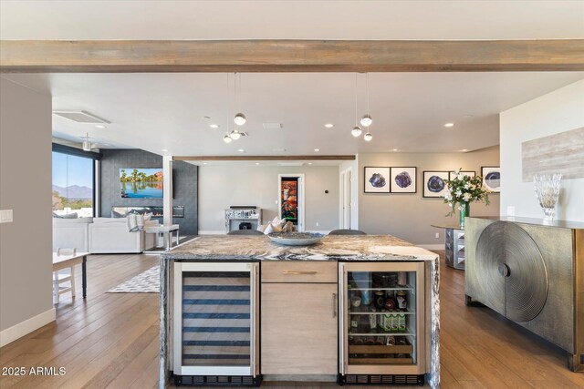 kitchen featuring pendant lighting, light stone countertops, beverage cooler, and a kitchen island