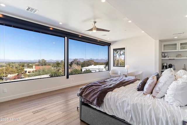 bedroom featuring a mountain view, light wood-type flooring, and ceiling fan