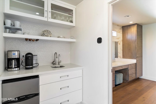 bar with white cabinetry, backsplash, hardwood / wood-style flooring, and stainless steel refrigerator