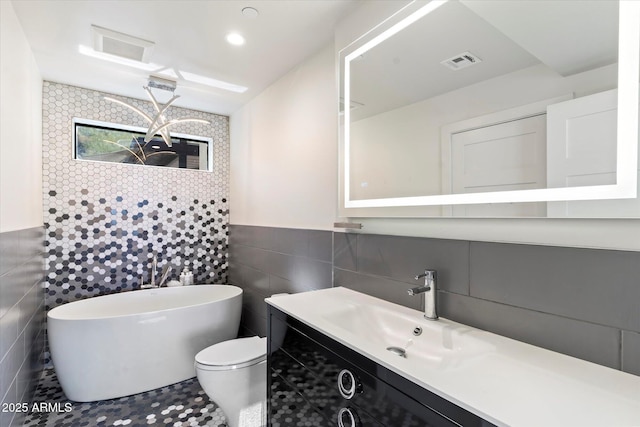 bathroom with tile walls, vanity, a tub, and toilet