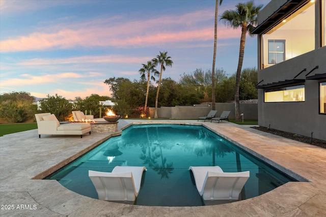 pool at dusk featuring a patio and an outdoor fire pit