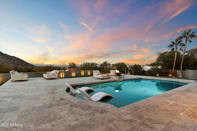 pool at dusk featuring a mountain view, an outdoor hangout area, and a patio area