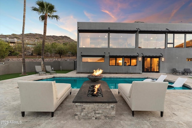 pool at dusk with a patio area and a fire pit