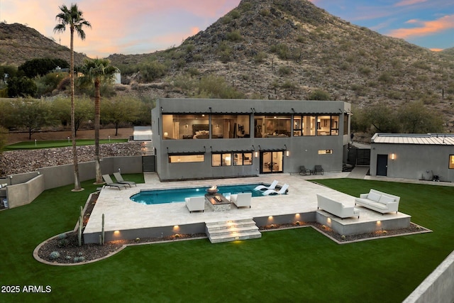 back house at dusk with a fenced in pool, a lawn, a mountain view, and a patio