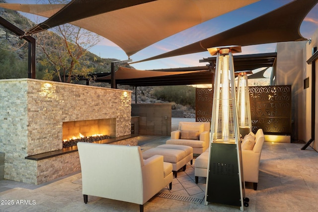 patio terrace at dusk featuring an outdoor stone fireplace