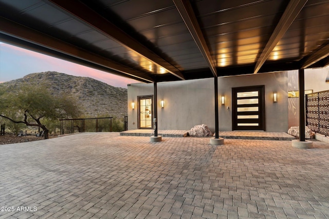 exterior entry at dusk featuring a mountain view and a patio area