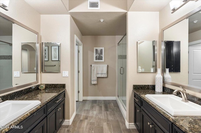 bathroom with a shower with door, vanity, a textured ceiling, and wood-type flooring