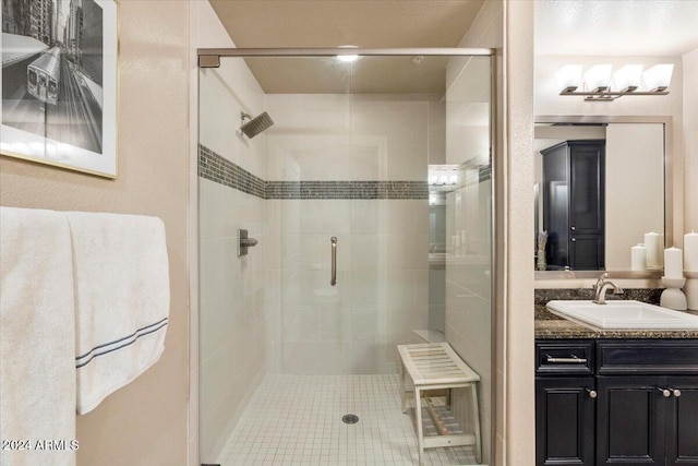 bathroom with a shower with door, vanity, and tile patterned floors