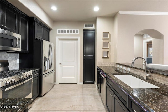 kitchen with decorative backsplash, dark stone countertops, stainless steel appliances, and sink