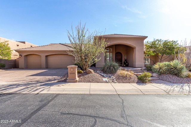 view of front of house with driveway, a tiled roof, a garage, and stucco siding