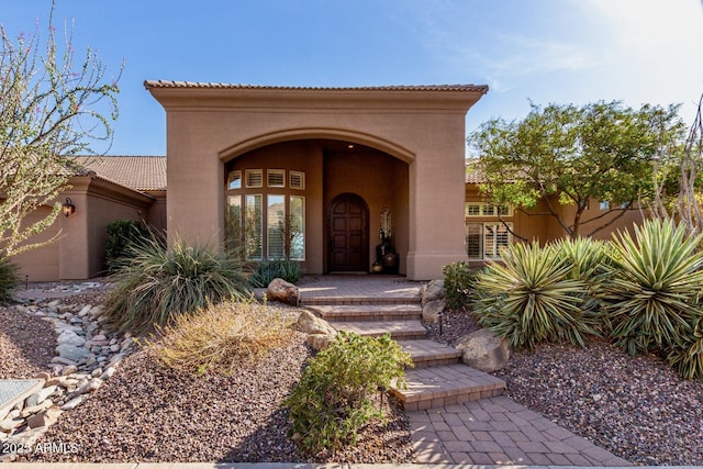 property entrance featuring a tiled roof and stucco siding