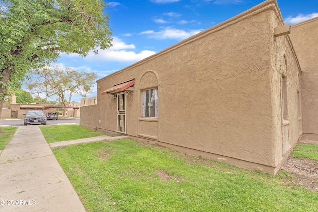 back of property featuring a lawn and stucco siding