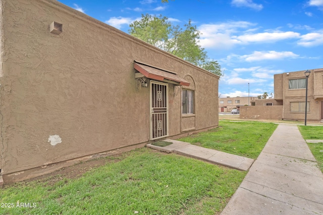 view of exterior entry featuring a yard and stucco siding