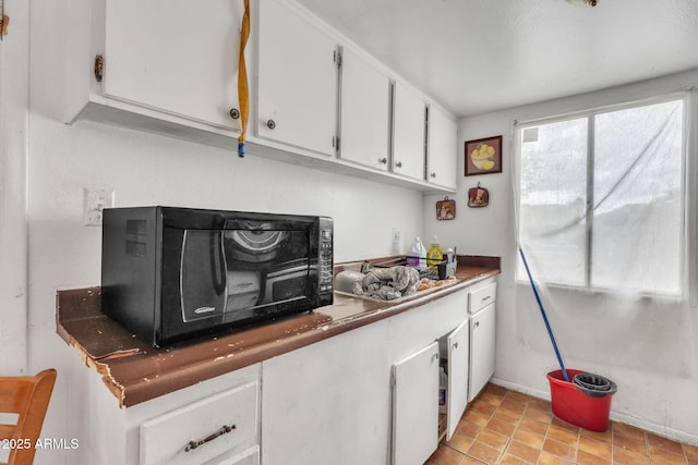 kitchen featuring white cabinets and black microwave