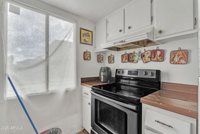 kitchen with under cabinet range hood, stainless steel electric stove, and white cabinets