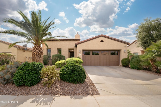 mediterranean / spanish home featuring an attached garage, concrete driveway, stucco siding, and a tile roof