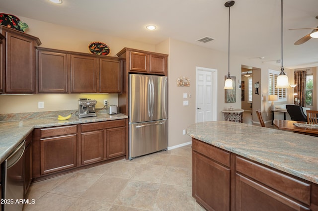 kitchen featuring light stone counters, decorative light fixtures, visible vents, ceiling fan, and stainless steel appliances